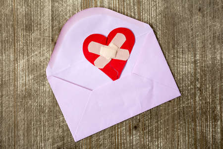 Envelope with broken heart on wooden tableの写真素材