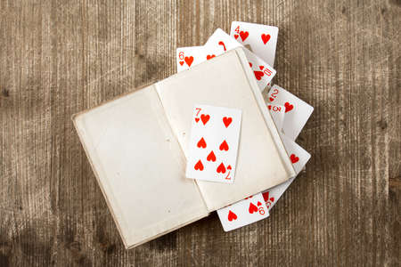 Open book and playing cards on wooden backgroundの写真素材