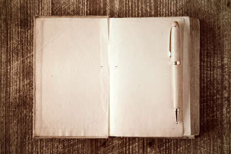 Closeup of open book and pen on wooden backgroundの写真素材