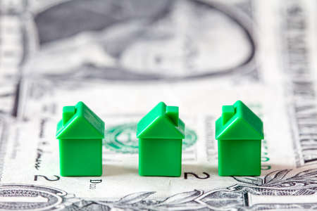 Miniature houses on dollar banknote background. Concept for property ladder, mortgage and real estate investmentの写真素材