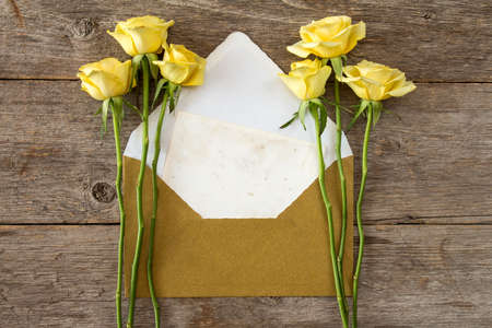 Yellow roses and love letter or note card with golden envelopeの写真素材