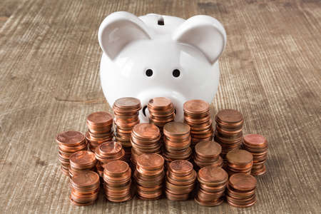 Stacks of copper coins (Euro cents) and white piggy bank