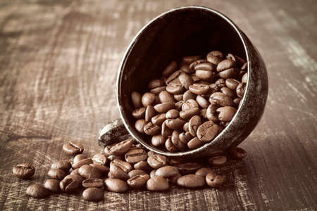 Black coffee cup and coffee beans on old wooden background.