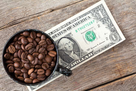 Cup of coffee beans on dollar banknote represent high or low price of coffee on stock marketの写真素材