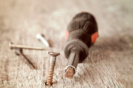 Old screwdriver and rusty screws on the wooden plankの写真素材