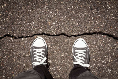 Man standing on cracked damaged city asphalt floorの写真素材