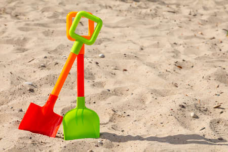 Two colorful plastic shovels on the beach sandの写真素材