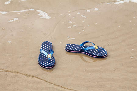 Sandal flip-flops lying on the seashore near the waterの写真素材