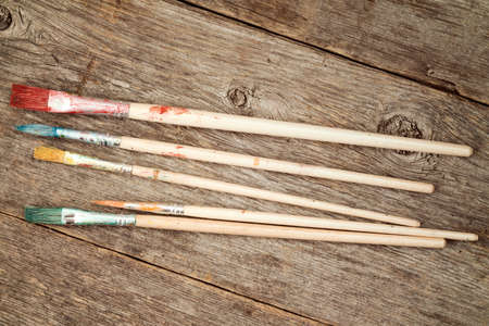 Set of dirty paint brushes on wooden background