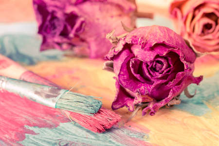 Abstract painting with dried roses and paint brushesの写真素材