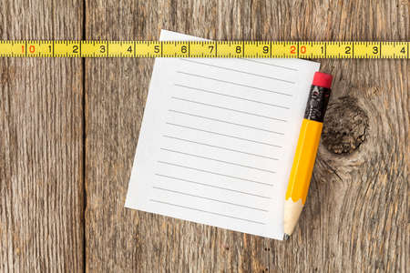 Blank note paper,pencil and tape measure on wooden textureの写真素材