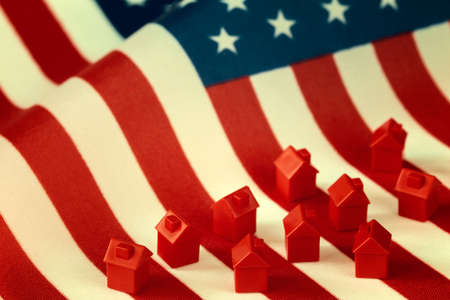 Mini houses against USA flag background. Citizenship, residence, property, real estate concept.