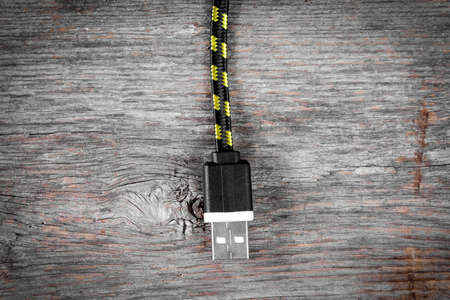Nylon braided USB cable hanging over wooden backgroundの写真素材