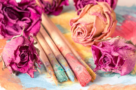 Abstract painting with dry roses buds and dirty paintbrushesの写真素材