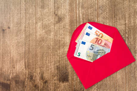Red envelope with Euro bills over wooden backgroundの写真素材