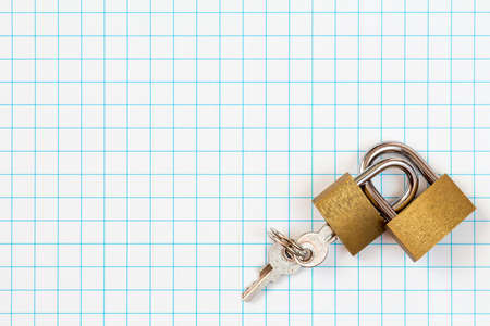 Two linked padlocks lying on squared paper backgroundの写真素材