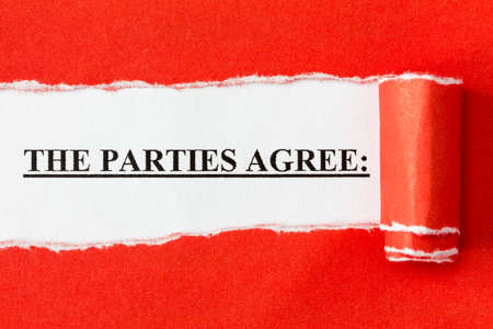 The phrase "THE PARTIES AGREE" appearing behind torn paper. Agreement,contract or deal concept.の写真素材