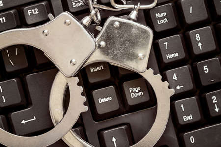 Online crime concept with handcuffs on computer keyboard