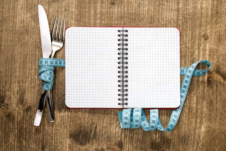 Cutlery tied with measuring tape and blank notebook for your textの写真素材