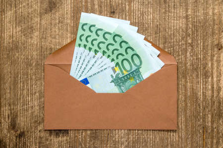 Brown envelope with Euro currency over wooden backgroundの写真素材