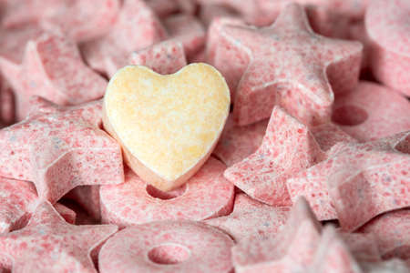 Heart-shaped candy in the pile of star-shaped candie