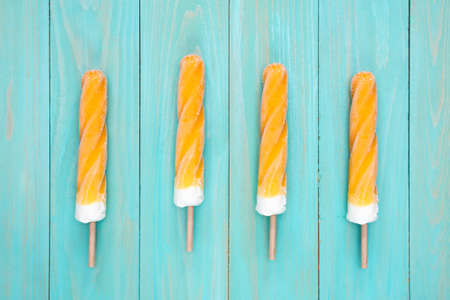 Frosty ice lolly of orange in a row on a blue backgroundの写真素材