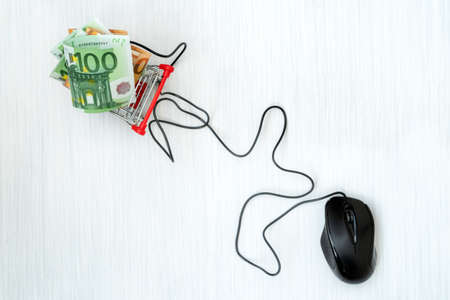 Buy and sell online. Computer mouse connected to shopping cart full of moneyの写真素材