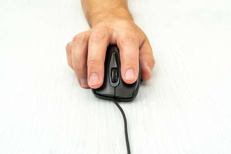 Man using a computer mouse on a white table. Front view.の写真素材