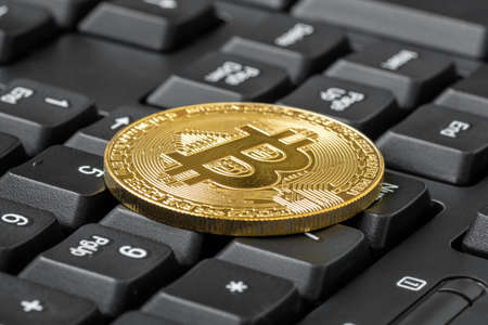 Golden BTC coin on computer keyboard.Close-up view.