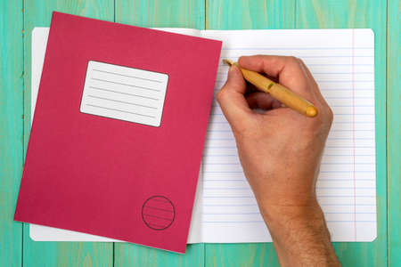 Man's hand writing in open school notebook.Top view.の写真素材