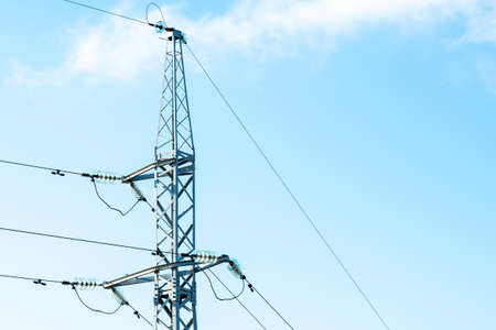 Power pylon with high voltage power lines with blue sky in the background