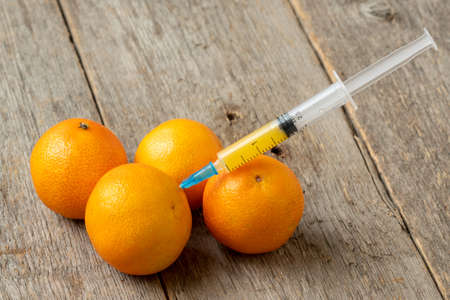 Syringe and mandarins. Concept for genetically modified food and cosmetic medicineの写真素材