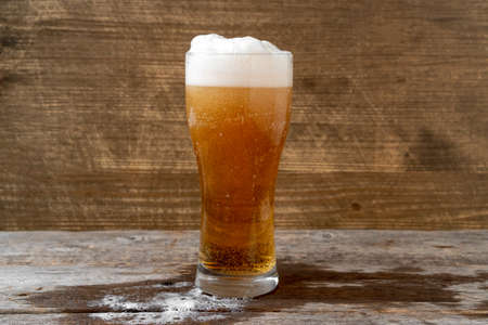 Lager beer with white froth and bubbles in glass mug 