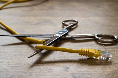 Internet ban, cencorship and interruption. Yellow Internet cable  cut by scissors.の写真素材