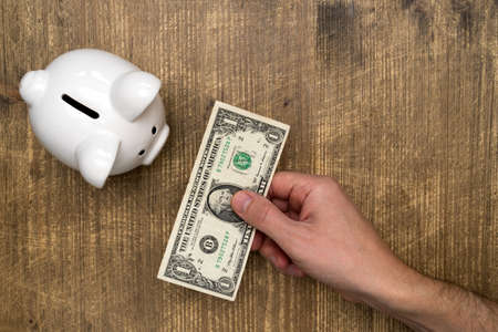 Hand with one dollar, saving in piggy bankの写真素材