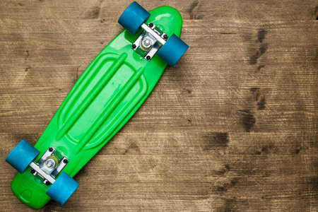 Overturned green skateboard lying on wooden background