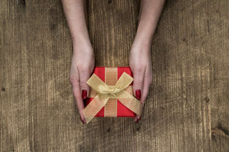 Flat lay of woman hands holding gift decorated with bow