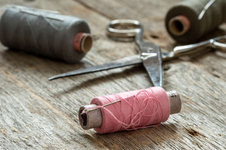 Spools of thread and scissors on wooden backgroundの写真素材