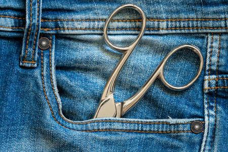 Closeup of metal scissors in blue jeans pocket