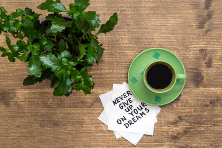 Never Give Up On Your Dreams - handwriting on a napkin with a cup of coffee and plantの写真素材