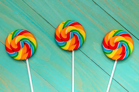 Three colorful  lolly pops on blue wooden background