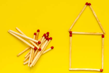 House from a matches (matches in the form of house) on a yellow background , flat layの写真素材