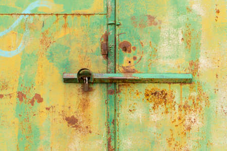 Rusted latch and padlock on old metal doors