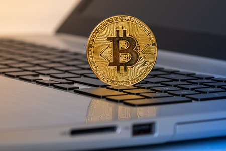 Golden Bitcoin coin on the laptop keyboard. Trading concept.