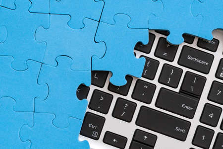 Computer keyboard hidden under jigsaw puzzle. Computer problems solving conceptの写真素材
