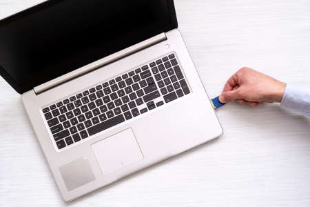 Hand inserting SD memory card into laptop slot の写真素材