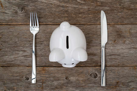 Savings consumer concept. Piggy bank with fork and knifeの写真素材