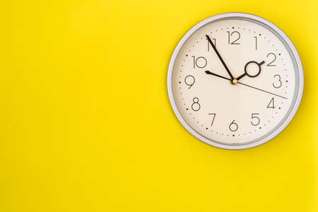 Clock on a yellow wall showing 1:55 o'clock