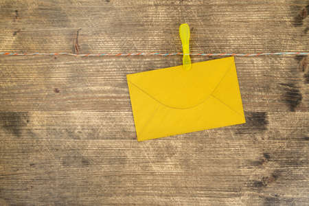 Gold envelope hang with clips and rope on wooden background
