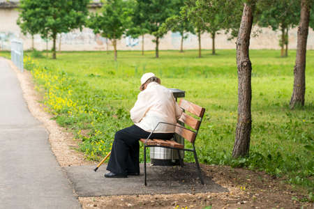 Lonely senior woman with a cane sitting on a benchの写真素材